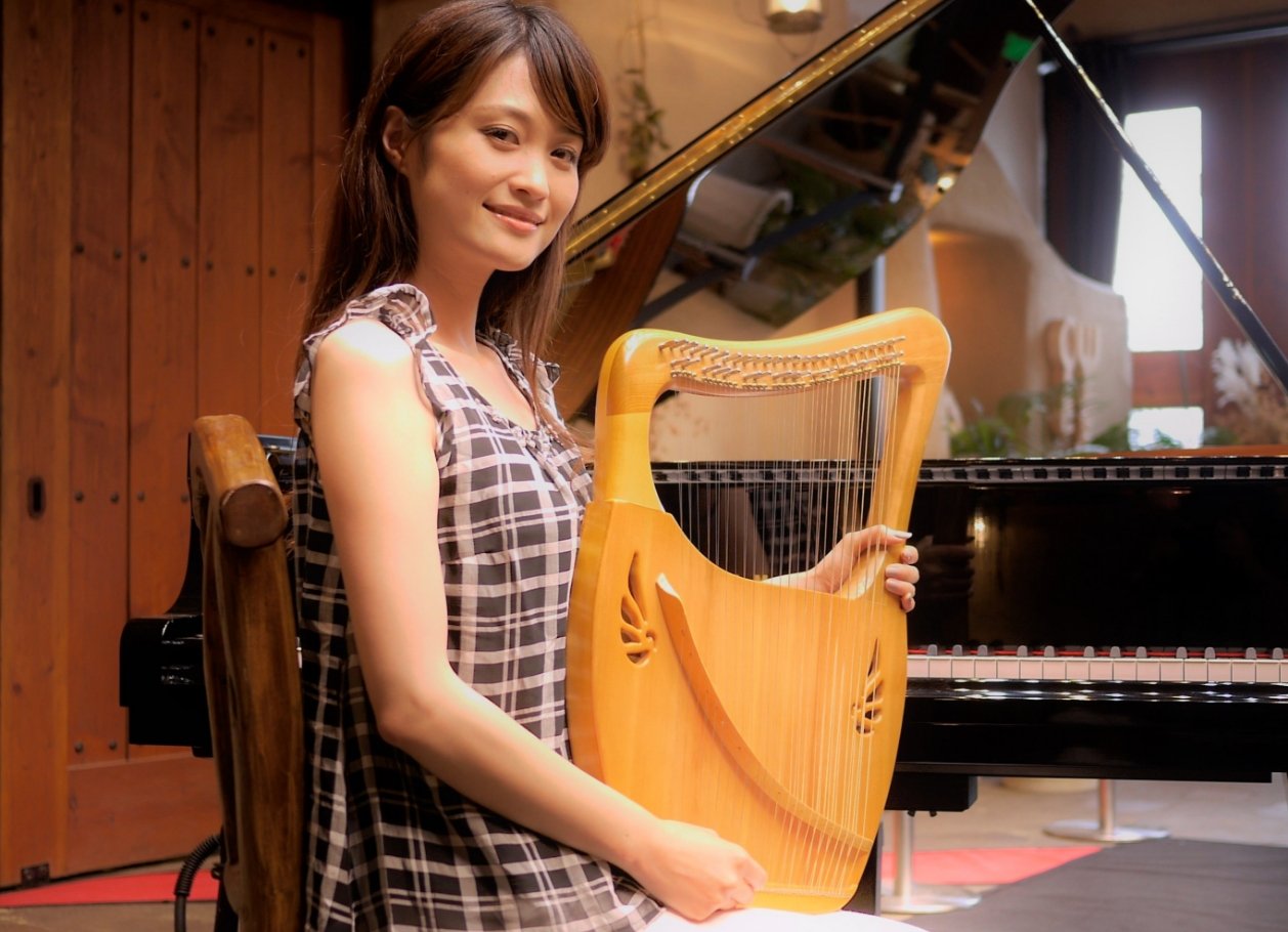 女性がピアノの前でライアーを持っている写真